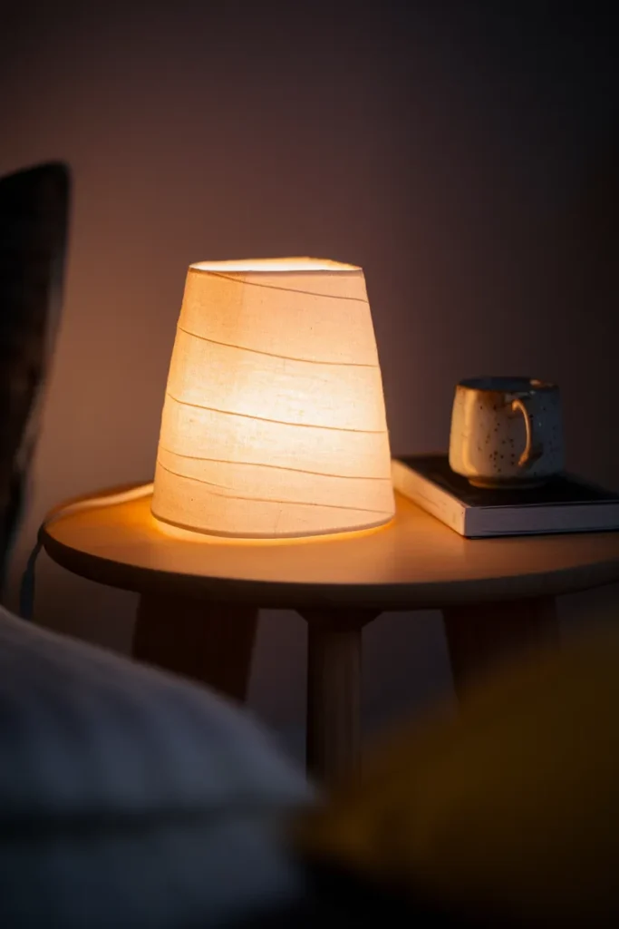 Cream linen lampshade casting warm 2700K light on a side table at night.