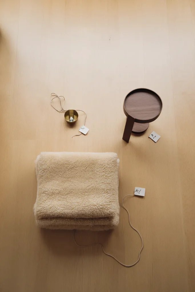 Three starter pieces for a small apartment corner laid out overhead with price tags throw, sconce, side table.