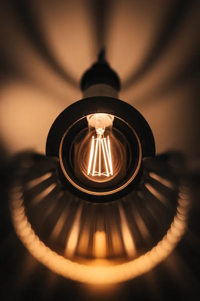 Close-up of a warm white 2700K LED bulb glowing in a black socket against a dark room.
