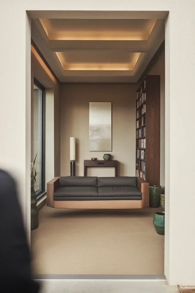 View through a doorway into a square living room with a floated sofa and console behind it.
