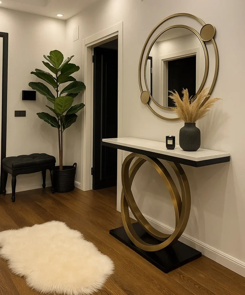 Modern entryway with a white marble console table on interlocking gold rings, a round gold-framed mirror, a black vase of pampas grass, a fiddle leaf fig, and a white sheepskin rug.