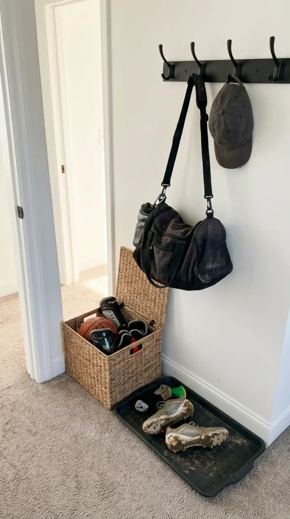 Sports gear drop zone in a teen boy bedroom with hook rail, open bin and boot tray