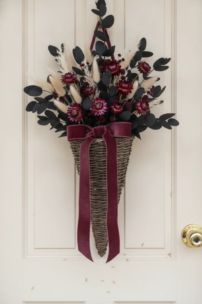 Whimsigoth dried bouquet in a cone basket on a cream door for moody Halloween decor