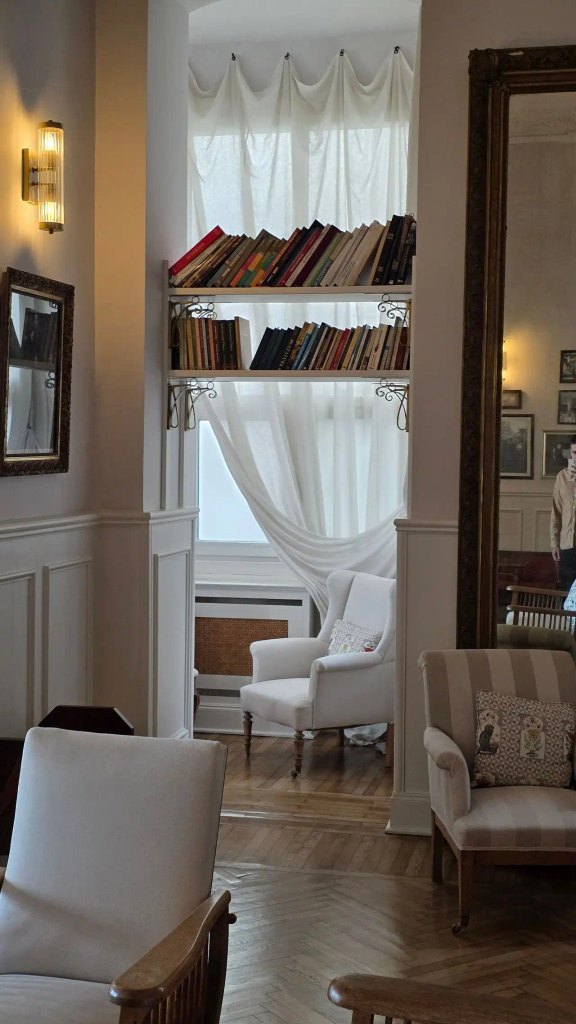 An elegant, classically styled sitting room with white wainscoting, comfortable armchairs