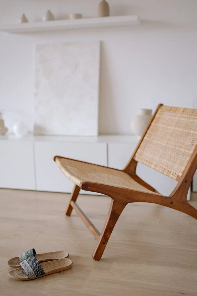 A mid-century modern wooden armchair with woven rattan seating resting on light wood floors