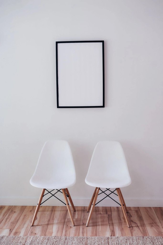 A vertical blank black picture frame hanging on a white wall